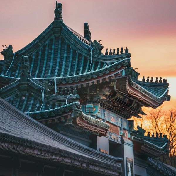 Happy traveler discovering ancient Asian temple with golden sunset