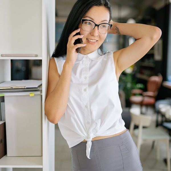 Professional Asian woman wearing trendy glasses with warm friendly smile in modern setting