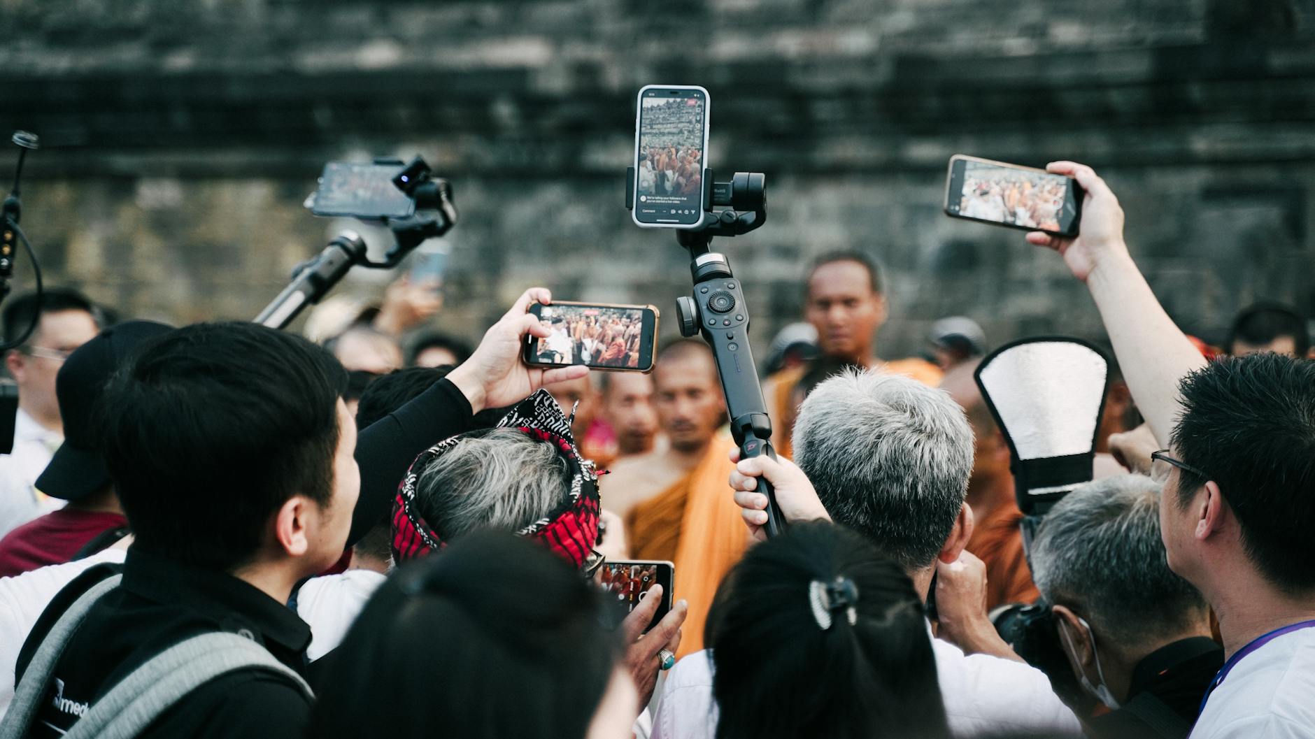 Traditional Asian temple ceremony with monks in orange robes and tourists respectfully observing customs