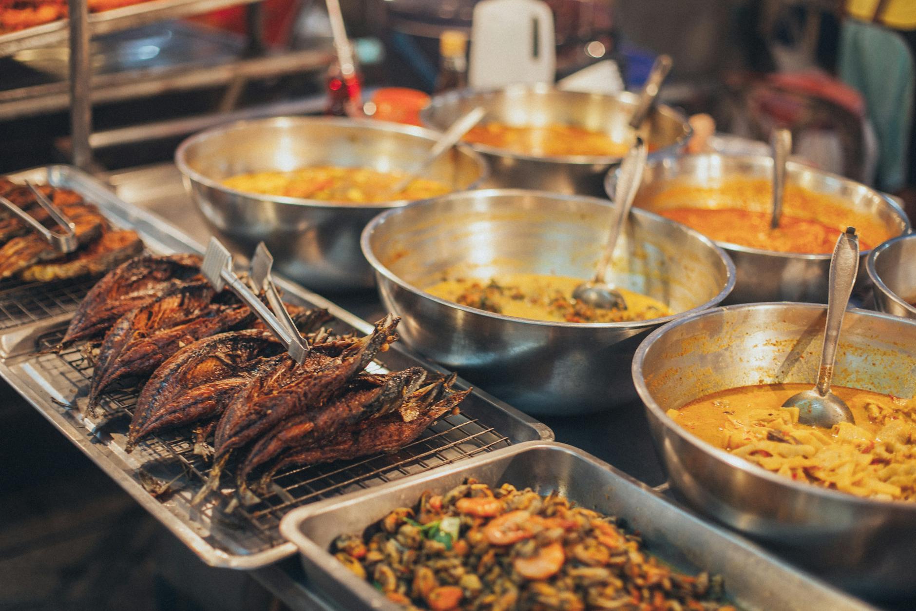 Vibrant Asian street food market with colorful dishes displayed on vendor carts and steaming woks